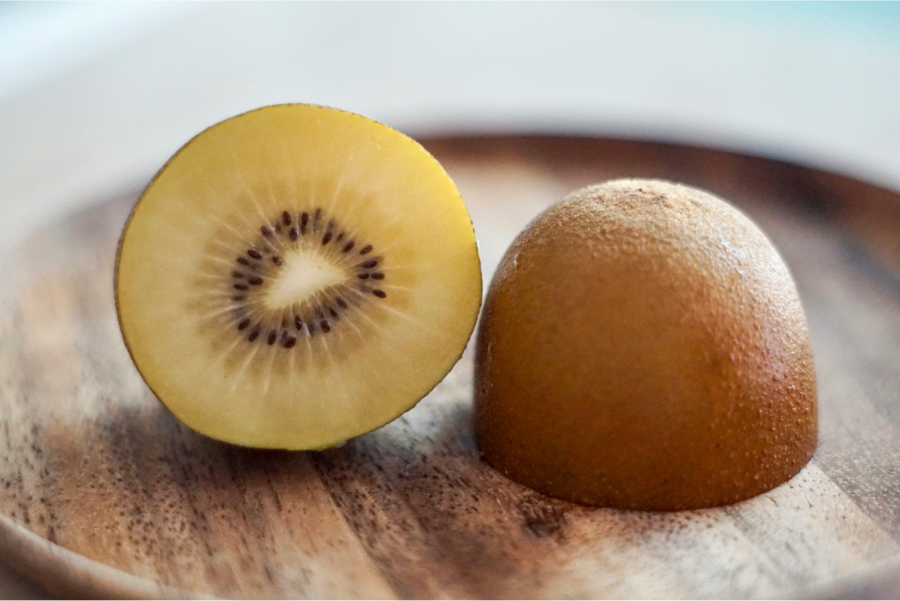 Halved Golden Kiwifruit on a wooden plate 